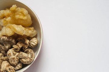 A close-up shot of some dried fish maw and mushrooms in a kitchen, these ingredient are in preparation stage
