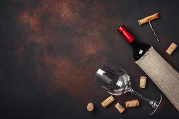 Bottle of wine, corkscrew and corks, on rusty background top view
