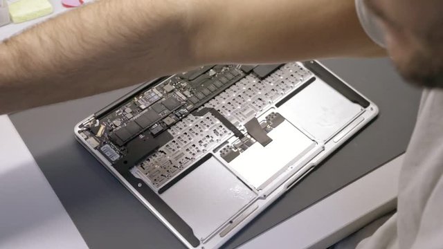The engineer repairs water damaged laptop (mac, computer)