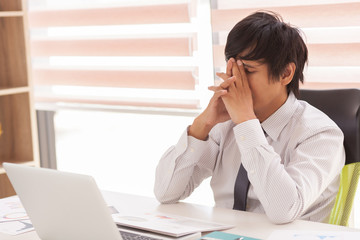The man are stressed at work in the office. Asian businessman stressful and headache with laptop computer. Young male with headache at office, feeling sick at work.