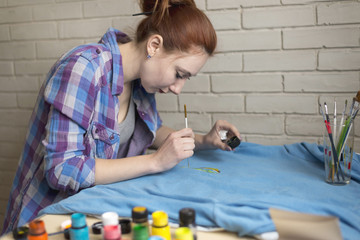 Photo of girl who drawing acrylic paints on blue clothes