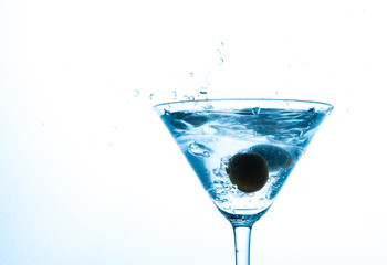 martini in glass with splashes and olives