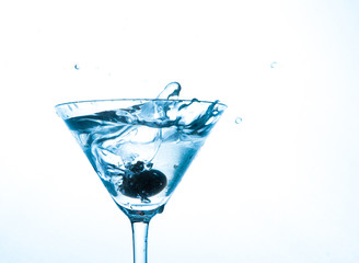 martini in glass with splashes and olives