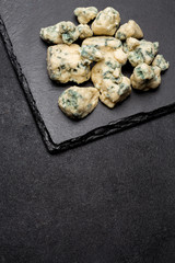 Slice of French Roquefort cheese on stone board