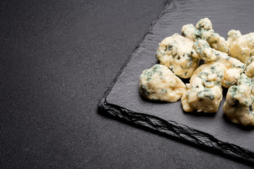 Slice of French Roquefort cheese on stone board