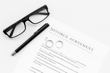 Divorce agreement. Wedding ring on document on white background top view copy space