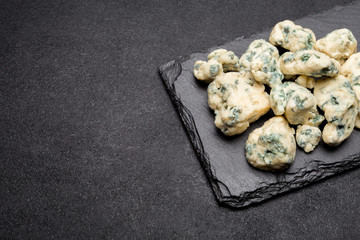 Slice of French Roquefort cheese on stone board