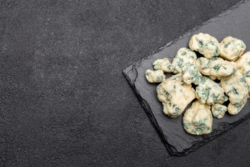 Slice of French Roquefort cheese on stone board