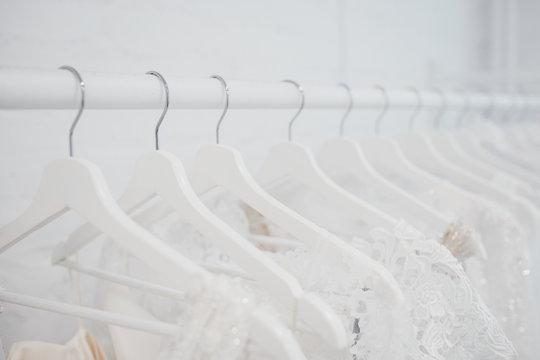 Wedding dresses for bride on hangers against white background loft store. Concept engagement, attributes, clothing, love.