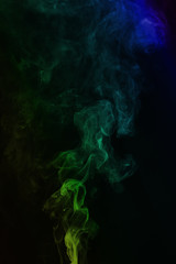 Multi-colored smoke on a black background. Tubers of smoke of different colors rise up.