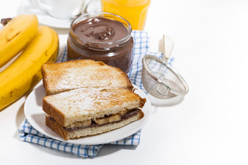 sweet sandwich with chocolate paste and banana for breakfast on white table, top view