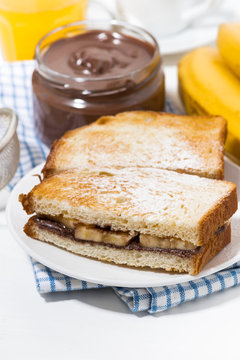 sweet sandwich with chocolate paste and banana for breakfast, vertical closeup