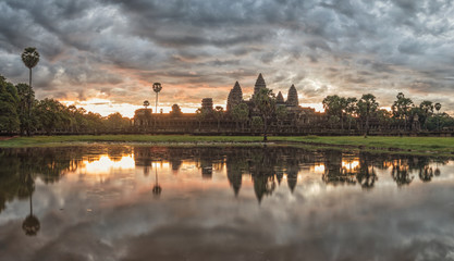 Fototapeta na wymiar Beautiful Cambodia ancient temple complex Angror Wat at sunrise with dramatic clouds over the towers and reflection in the pond. Very famous travel destination. 