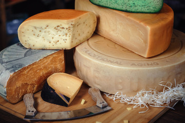 Wooden board with various kinds of tasty on the table with knives green cheese bunker cheese