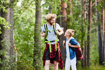 Fototapeta premium Two friendly boy scouts with backpacks walking in the forest and having talk on their way to camp