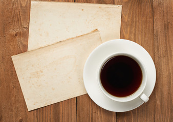 Obraz na płótnie Canvas cup of coffee on wooden boards, blank paper sheet with place for text - holiday and greeting concept