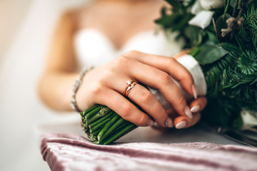 Closeup photo of bride’s hand with ring and flowers