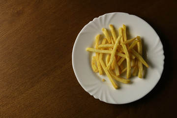 Tasty fried potatoes fries chips on the white plate on the black wooden background