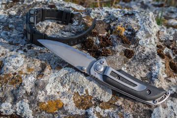 Folding knife and men's watch on stone