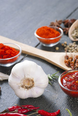 fresh and dried chili fruits, peppercorn, pepper powder, sauce and garlic, bay leaves on old black wooden table background