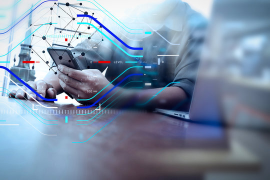 designer hand working and smart phone and laptop on wooden desk in office with london city background