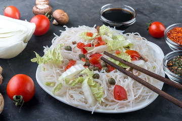 Rice noodles with vegetables, mushrooms and soy sauce in the ceramic plate  on dark background.