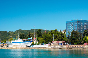 A boat and a cafe near the blue sea and resort town on background