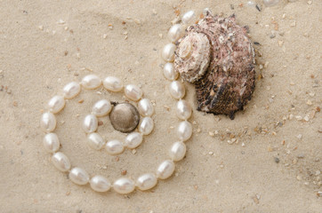 Perlenkette und Schnecke im Sand