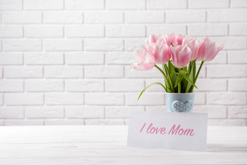 Composition with greeting card and tulips for Mother's Day on table