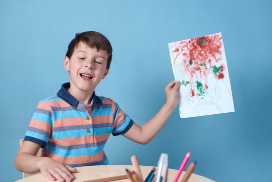 Caucasian boy demonstrating picture he has drawn with pencils and felt pens.