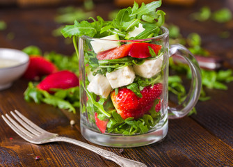 Fresh vegetable strawberry salad in glass jar on natural rustic desk.