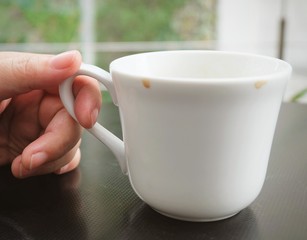 Hand Holding Empty Cup of Coffee on The Table