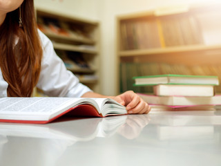 young Asian student Woman reading a book in library. Portrait of college girl reading book in...