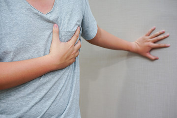 close up on man hand touching his chest after heart attack symptom , mental health concept