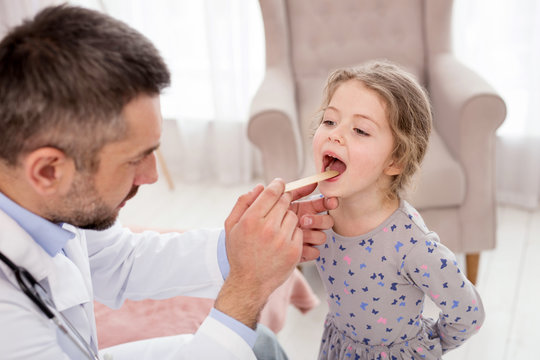 Attentive Doctor. Determined Professional Doctor Examining His Patient And Looking In Her Throat