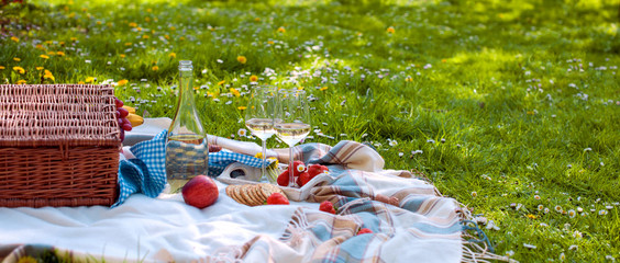 picnic basket and food. A bottle of wine and two glasses. Romanica. Green meadow with flowers....