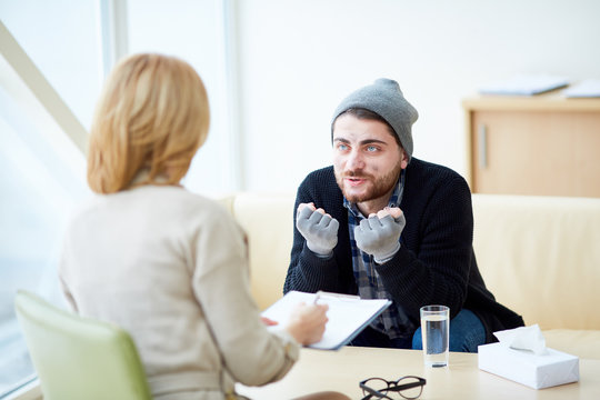 Young refugee in need explaining his problems to psychologist during session in social support center