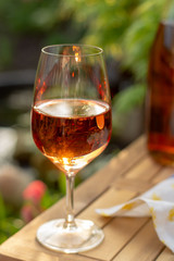 Cold rose wine in glasses served on outdoor terrace in garden with flowers in sunny day