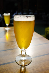 One cold light unfiltered beer in glass served on sunny outdoor terrace in garden