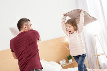 Obraz premium Happiness. Joyful charming daughter spending with her daddy and having a pillow battle