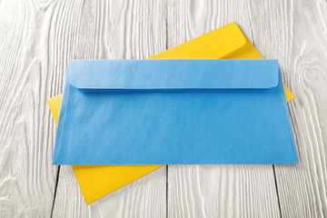 two yellow and blue envelopes with letters on white wooden background.  Blanks for the designer. Concepts, ideas for postal services and e-mail, travel.