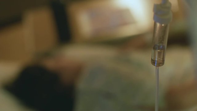 Hospital Bed Female Patient IV Drip Scene Out of Focus Woman Giving Birth Stress Agony Pain in Background