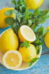Yellow lemons with mint leaves, wooden background