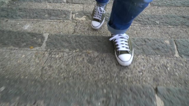 man with blue geans and sneaker shoes goes up the stairs