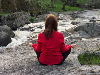 Mujer joven haciendo yoga frente al río