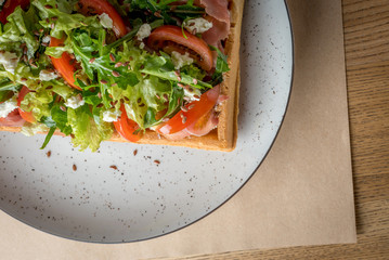 Savory Belgian waffles with salmon, salad and tomato. Perfect breakfast for long day. Restaurant menu or recipe concept