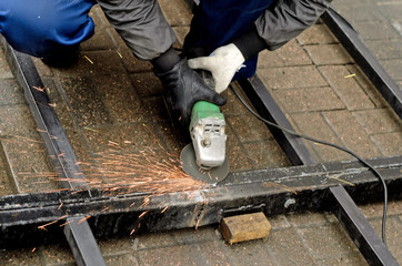 worker in gloves cleans the angle grinder