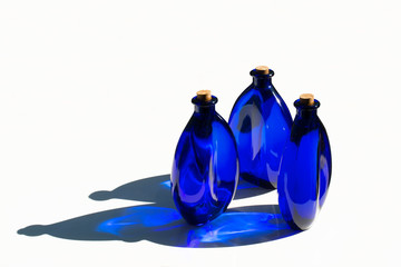 Blue solar water in blue glass bottles sealed with cork stoppers. Isolated on white background.