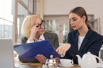 New employee. Successful aged businesswoman discussing statistics with her apprentice while having lunch