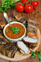 BBQ fish wrapped in grape leaves and bacon on the cutting board